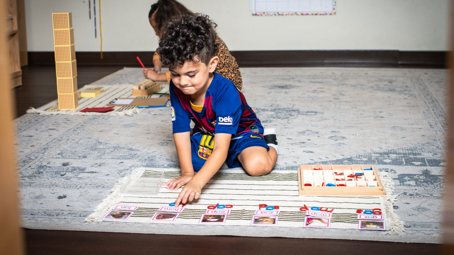 A child learning how to spell using flashcards and toy letters on a rug