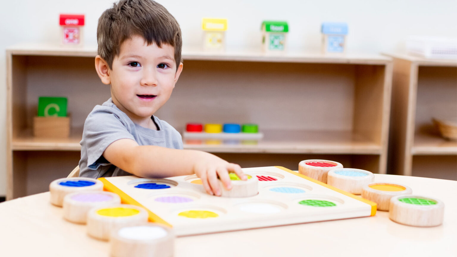 A boy playing matching colors using round, wooden toys with color patches